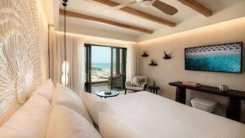 Ein Hotelzimmer mit Bett, Schreibtisch, Sessel, Fernseher und Blick auf den Strand.