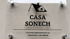 Un letrero con un icono de casa y el texto 'CASA SONECH' junto con dos líneas de códigos alfanuméricos.