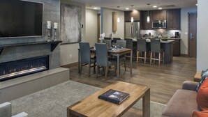 Una sala de estar moderna con chimenea, comedor y cocina.