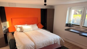 A bedroom with a large bed, a bench, a radiator, and a window with a view of the outside. - Smart, central apartment - garden - barbecue (Bückeburg)