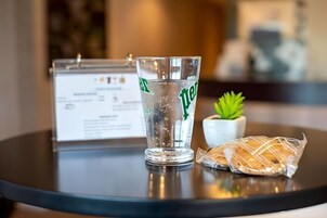 A glass of water on a table with a menu and a small plant beside it.