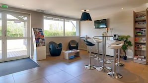 Una zona d'entrada moderna amb una finestra gran, un taulell de recepció i una zona de seients amb cadires i una barra.