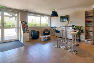 A modern reception area with a large window, a reception desk, and a seating area with chairs and a bar.