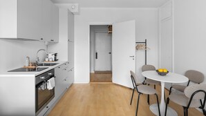 A modern kitchen with a built-in oven, a sink, and a dining area with a round table and chairs.