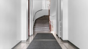 A hallway leading to a staircase with a dark carpet and white walls.