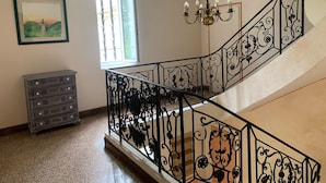 A staircase with ornate black railings, a chandelier, a dresser, and a framed painting. - Large villa 10 minutes from the Nîmes Arena (Nîmes)