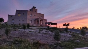 A large, historic building with multiple arches and a prominent entrance, situated on a hill with sparse vegetation. - Essaouira countryside, villa, swimming pool, 2 hectares, olive trees, mountain view, .... (essaouira)