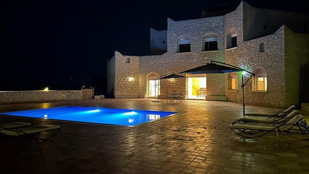A stone building with a swimming pool, outdoor seating, and a well-lit entrance. - Essaouira countryside, villa, swimming pool, 2 hectares, olive trees, mountain view, .... (essaouira)