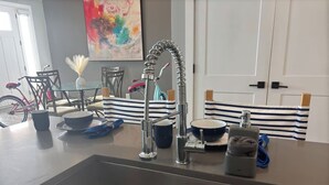 Una cocina con un lavamanos de acero inoxidable, una bicicleta y una silla a rayas.