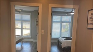 Un pasillo con dos dormitorios, cada uno con cama y ventana.