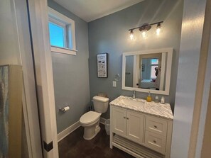 Et badeværelse med toilet, håndvask og spejl.