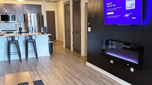A modern kitchen with a bar area, a flat-screen TV mounted on the wall, and a built-in aquarium. - King Sky Suite | 1 Mile to Piedmont Park | Parking (Atlanta)