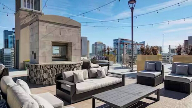A rooftop patio with outdoor seating, a stone fireplace, and a city skyline view. - King Sky Suite | 1 Mile to Piedmont Park | Parking (Atlanta)