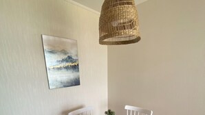 A round dining table with four white chairs, a woven pendant light, a small potted plant, and a cereal box on the table. - The most comfortable apartment in San Fernando (San Fernando)