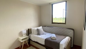 A bedroom with a bed, a bedside table, a window, and a view of greenery outside. - The most comfortable apartment in San Fernando (San Fernando)