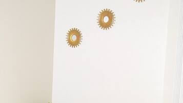 Un lit avec une couette blanche matelassée et des oreillers, une serviette pliée, et trois décorations murales en forme de soleil.