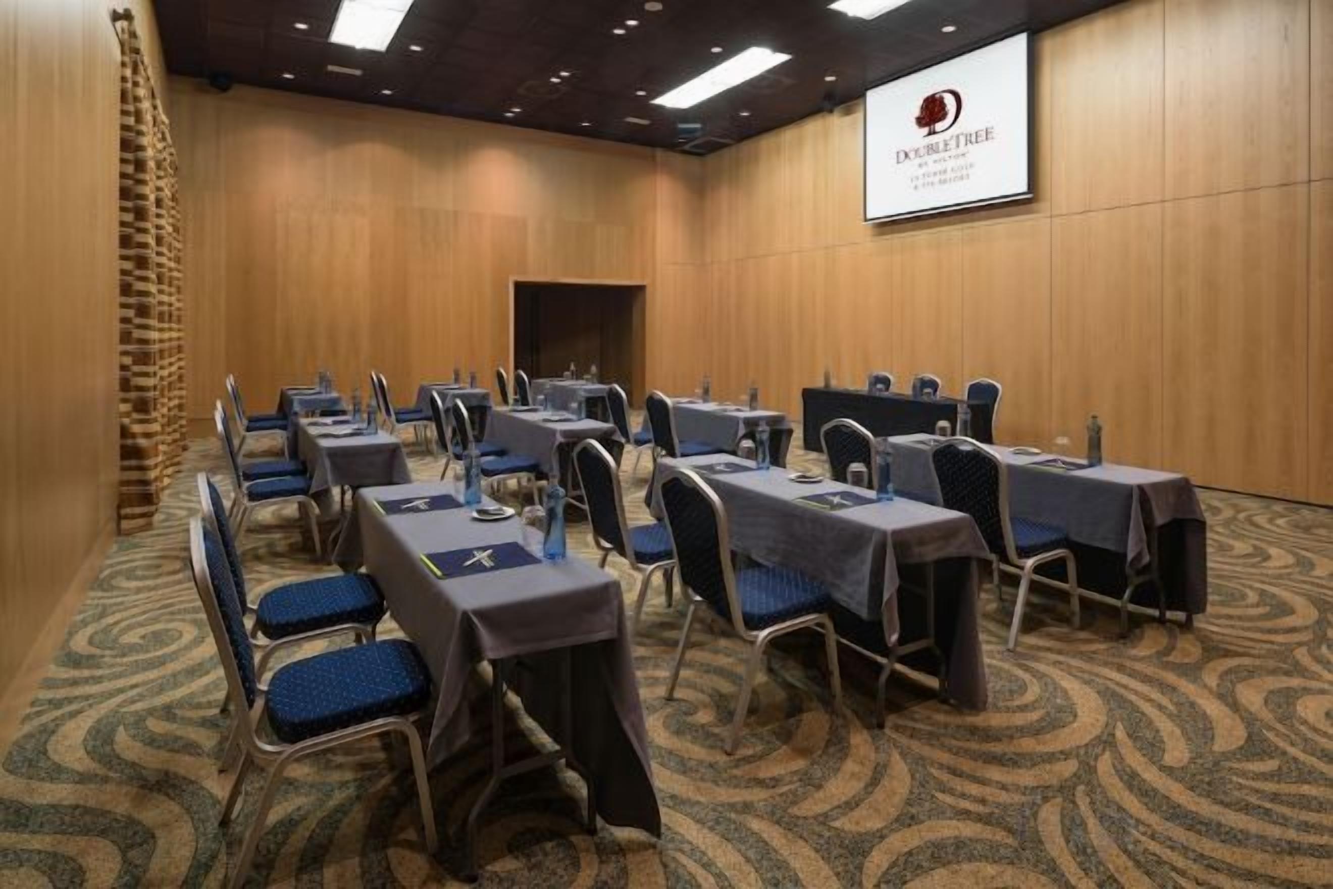 Una sala de conferencias con mesas y sillas dispuestas para reuniones.