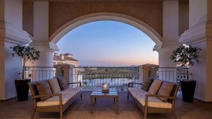 A balcony with two wicker sofas, a small table, and potted plants. - DoubleTree by Hilton La Torre Golf & Spa Resort (Murcia)