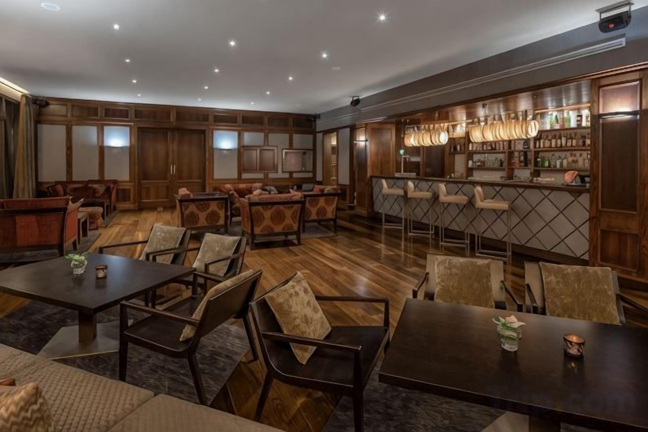 Amplia sala de estar con diversas opciones de asientos, un bar con estante para vinos y un televisor montado en la pared.