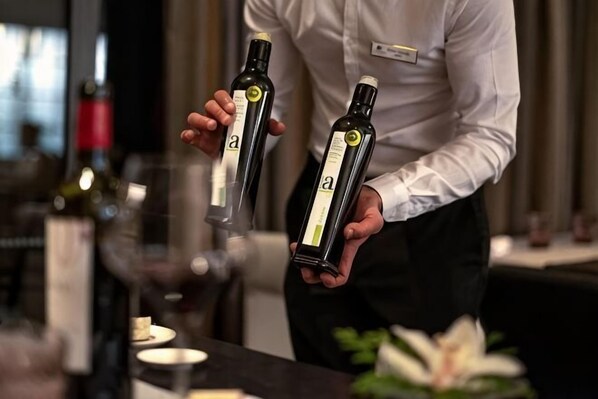 A person holding two bottles of wine with labels, in a setting with a bar counter and various bottles in the background. - DoubleTree by Hilton La Torre Golf & Spa Resort (Murcia)