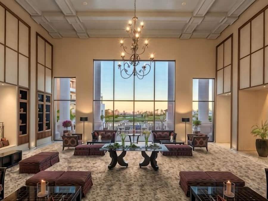 Um hall amplo com uma grande janela, um lustre e disposição de assentos.