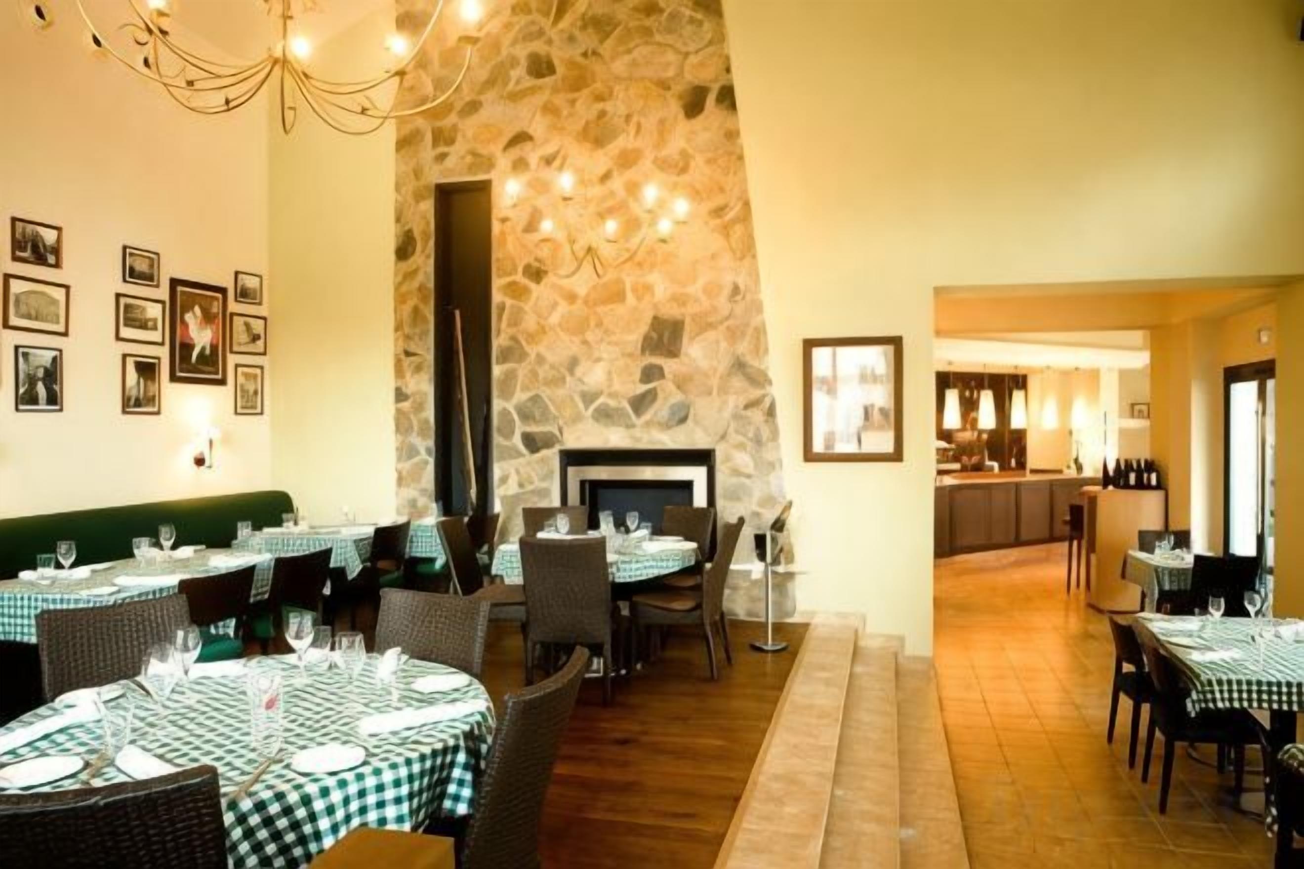 Un restaurante con mesas redondas, pared de piedra y chimenea.