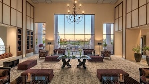 A spacious lobby with a large chandelier, seating area, and large windows offering a view. - DoubleTree by Hilton La Torre Golf & Spa Resort (Murcia)