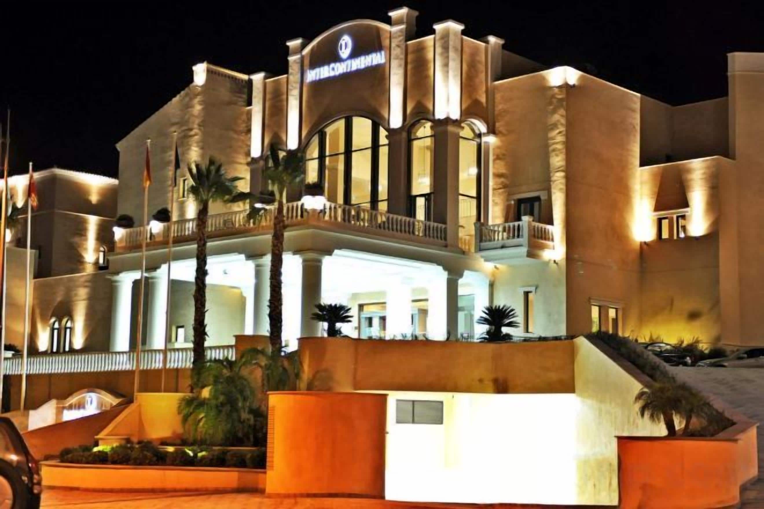 Un hotel con una entrada destacada, un balcón y una bandera.