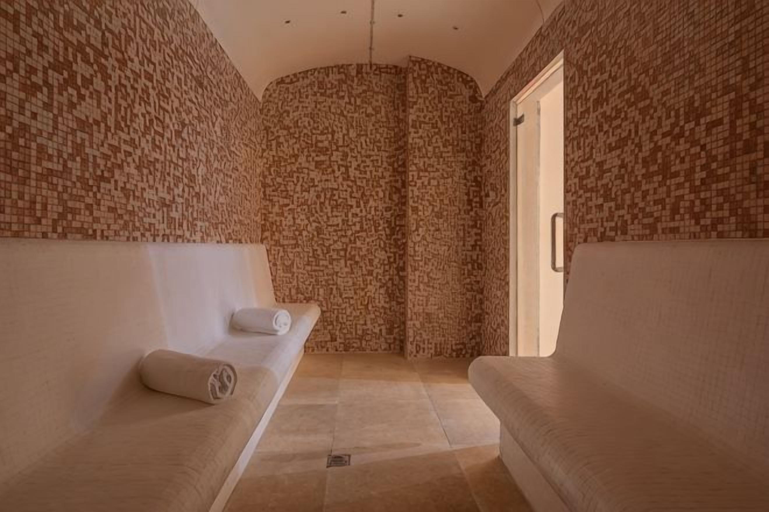Un cuarto de spa con dos bancos, una pared con azulejos y una puerta.