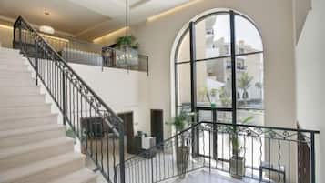 A spacious interior with a staircase, large windows, and indoor plants.