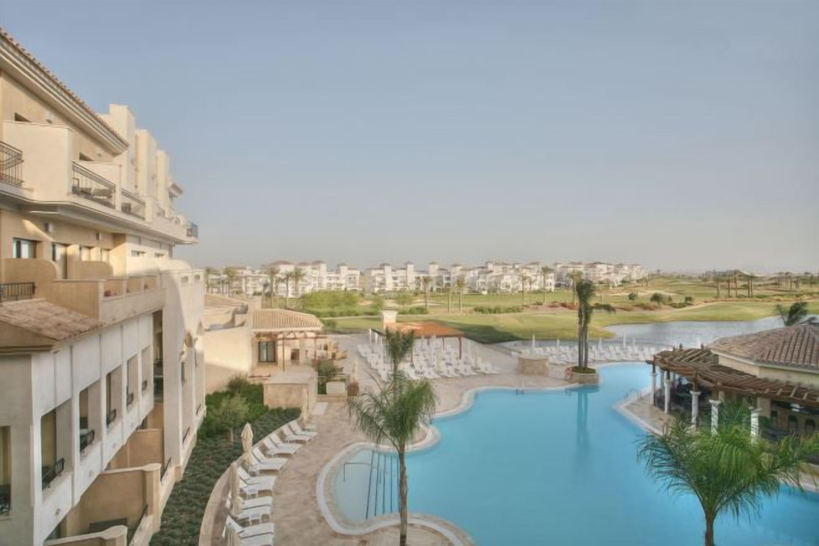 A resort with a swimming pool, a view of the surrounding area, and a building with balconies.