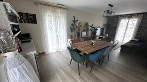 A spacious living area with a wooden dining table, blue chairs, and a sofa.