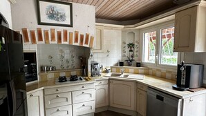 A kitchen with wooden ceiling beams, white cabinetry, a stove, a sink, and a dishwasher.