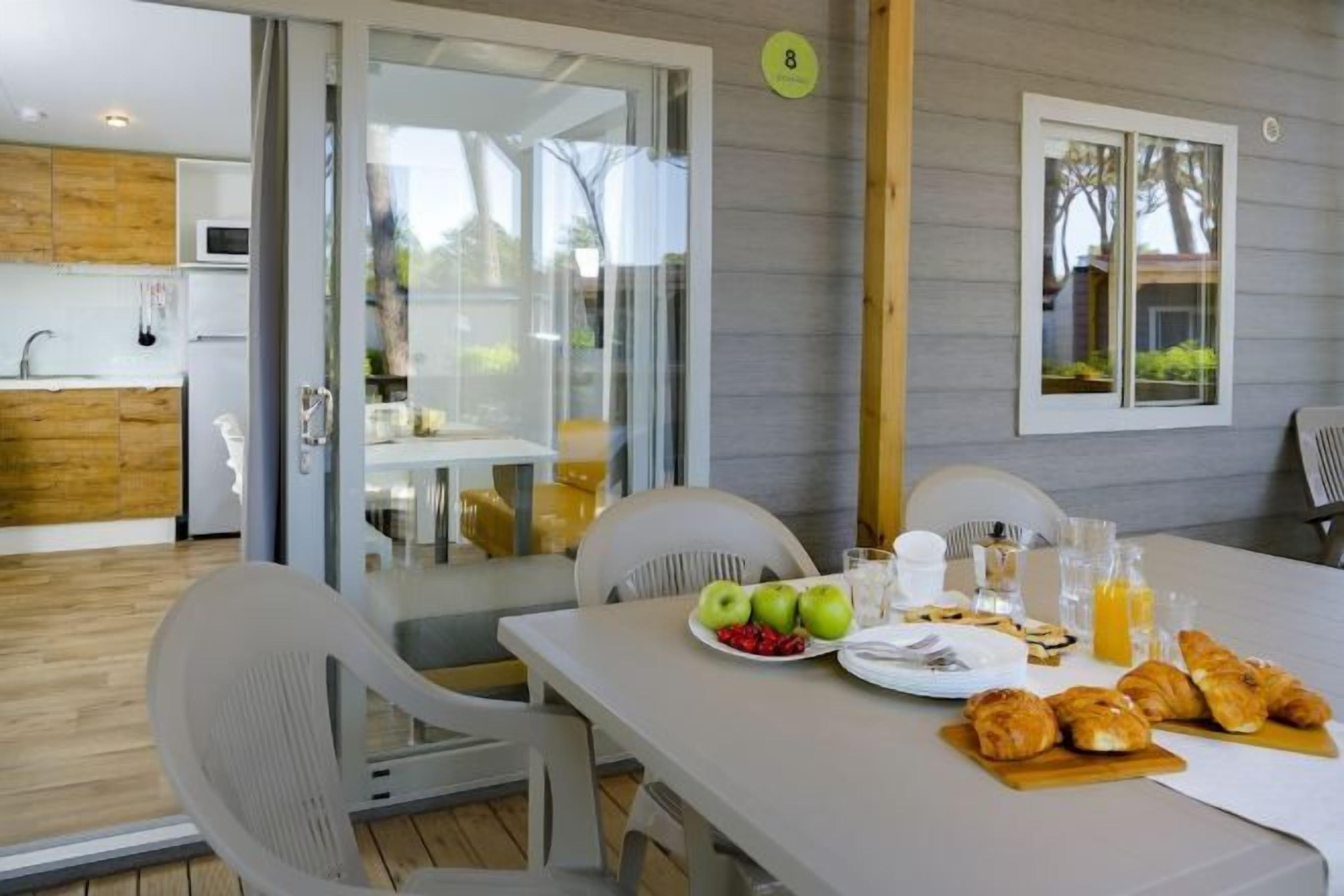 Een eetgedeelte met een ontbijt aan tafel, inclusief croissants, appels en sap.
