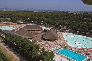 A resort with multiple swimming pools, thatched-roof structures, and a view of a forested area. - hu Park Albatros Village (San Vincenzo)
