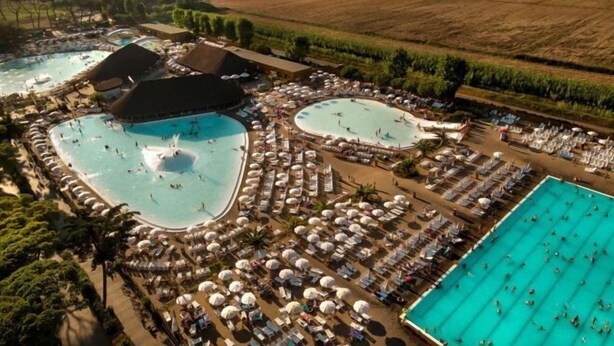 Vue aérienne d’un complexe hôtelier doté de plusieurs piscines, de chaises longues et de parasols.