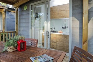 Una terraza de madera con una mesa, sillas y un farol rojo.
