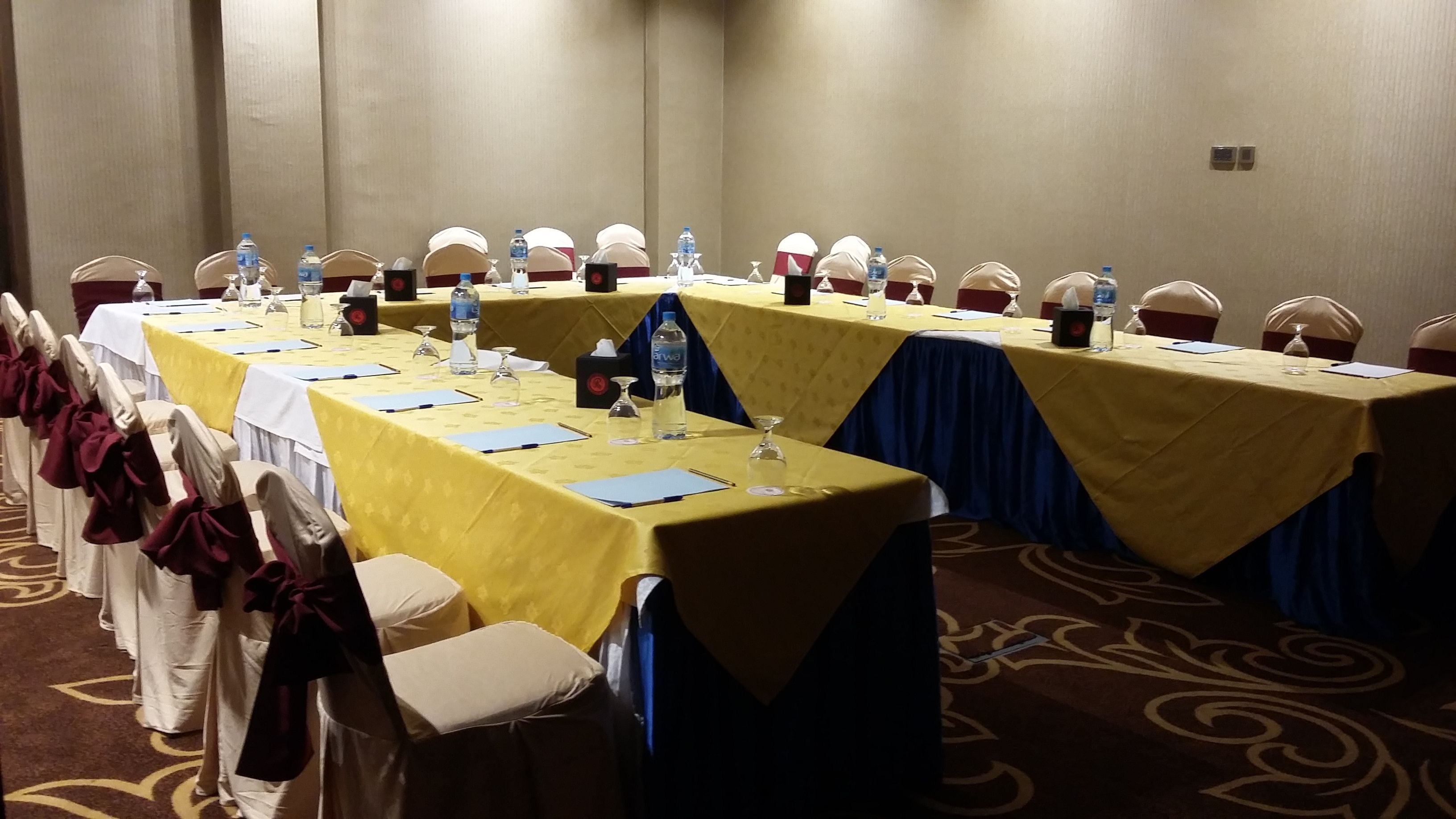 Una sala de conferencias con varias mesas, sillas y botellas de agua.
