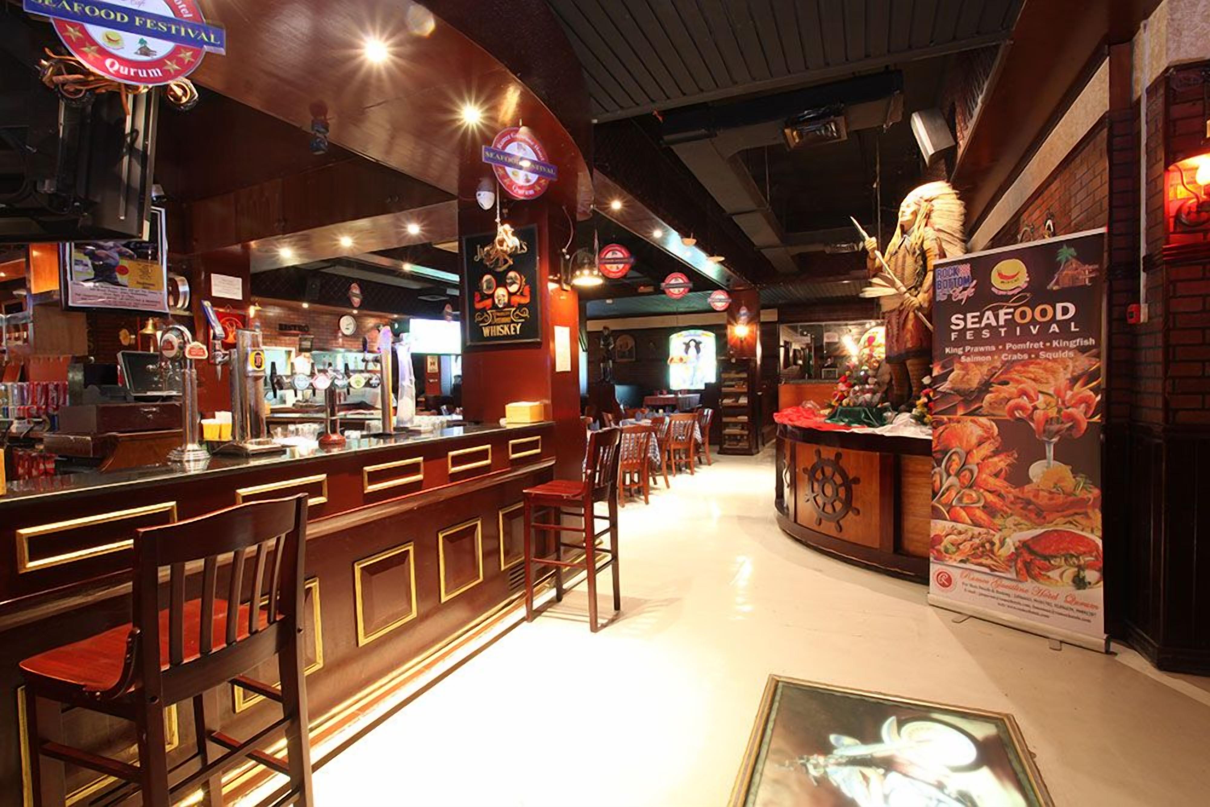Interior de un restaurante de mariscos con zona de bar, mostradores de madera y un cartel anunciando un festival de mariscos.