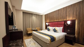 Une chambre d’hôtel avec un grand lit, un bureau, une chaise, une petite table et un téléviseur.