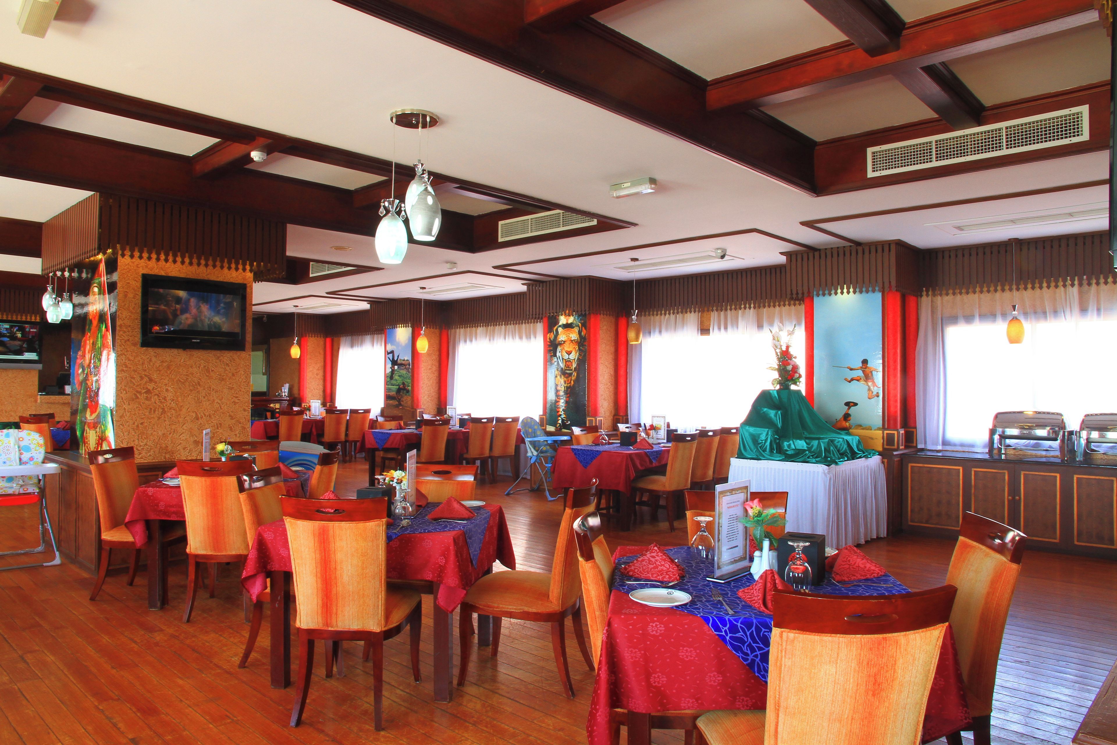 A restaurant with wooden floors, tables with red tablecloths, and chairs.