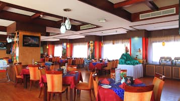 A restaurant with wooden floors, tables with red tablecloths, and chairs.