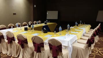 A conference room with a long table, chairs with bows, water bottles, and a whiteboard.
