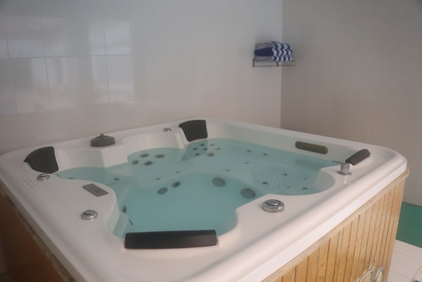 A hot tub with multiple jets, a control panel, and a towel rack on the wall. - Ramee Guestline Hotel (Muscat)