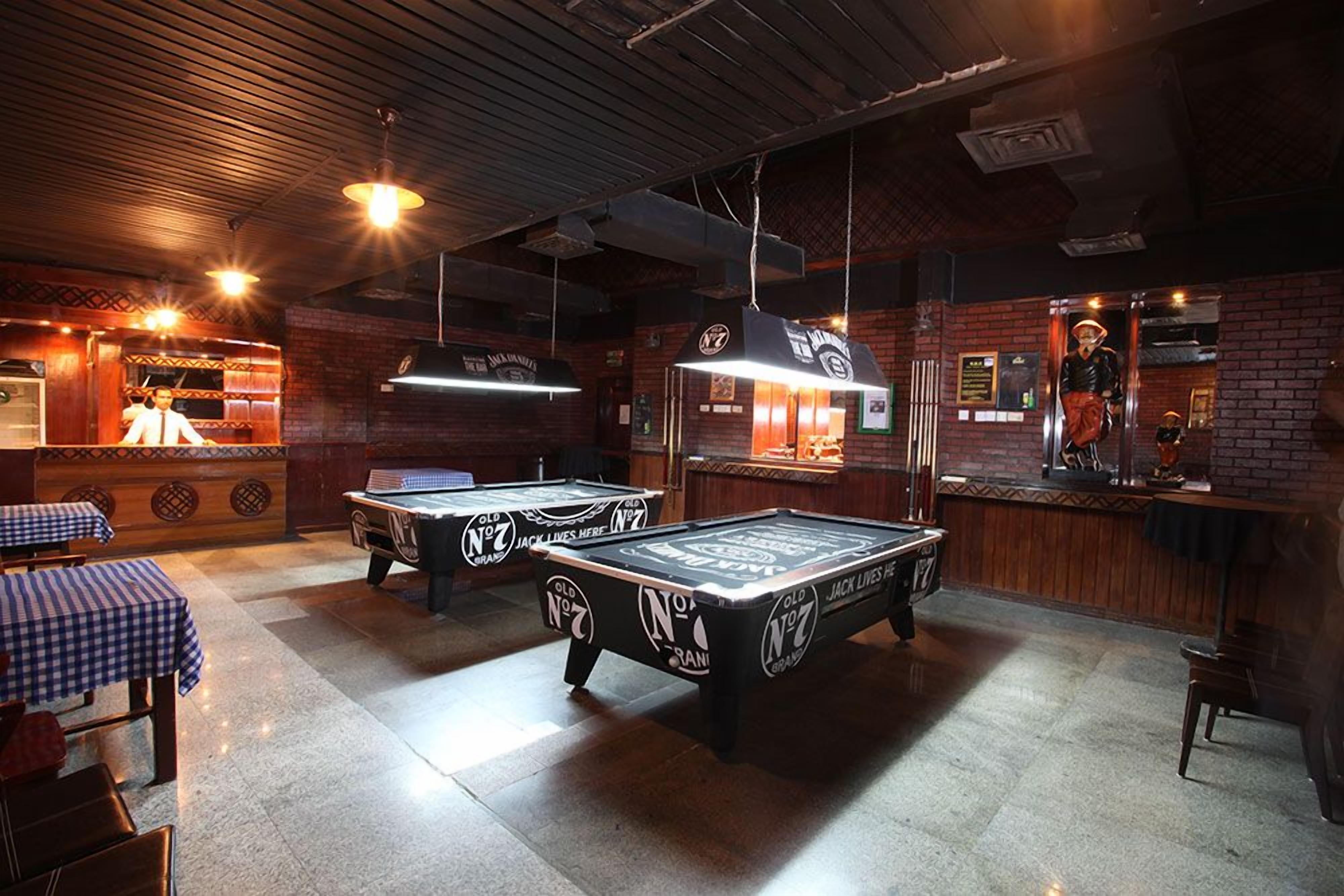 A billiards room with tables and a bar area.
