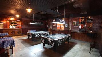 A billiards room with tables and a bar area.