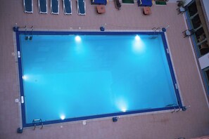 A rectangular swimming pool with a blue border, surrounded by a tiled deck. - Ramee Guestline Hotel (Muscat)