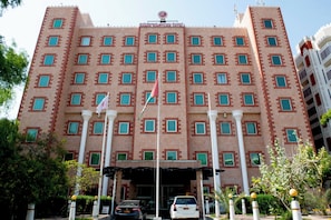 Un hotel de varios pisos con fachada simétrica, numerosas ventanas y una entrada central.