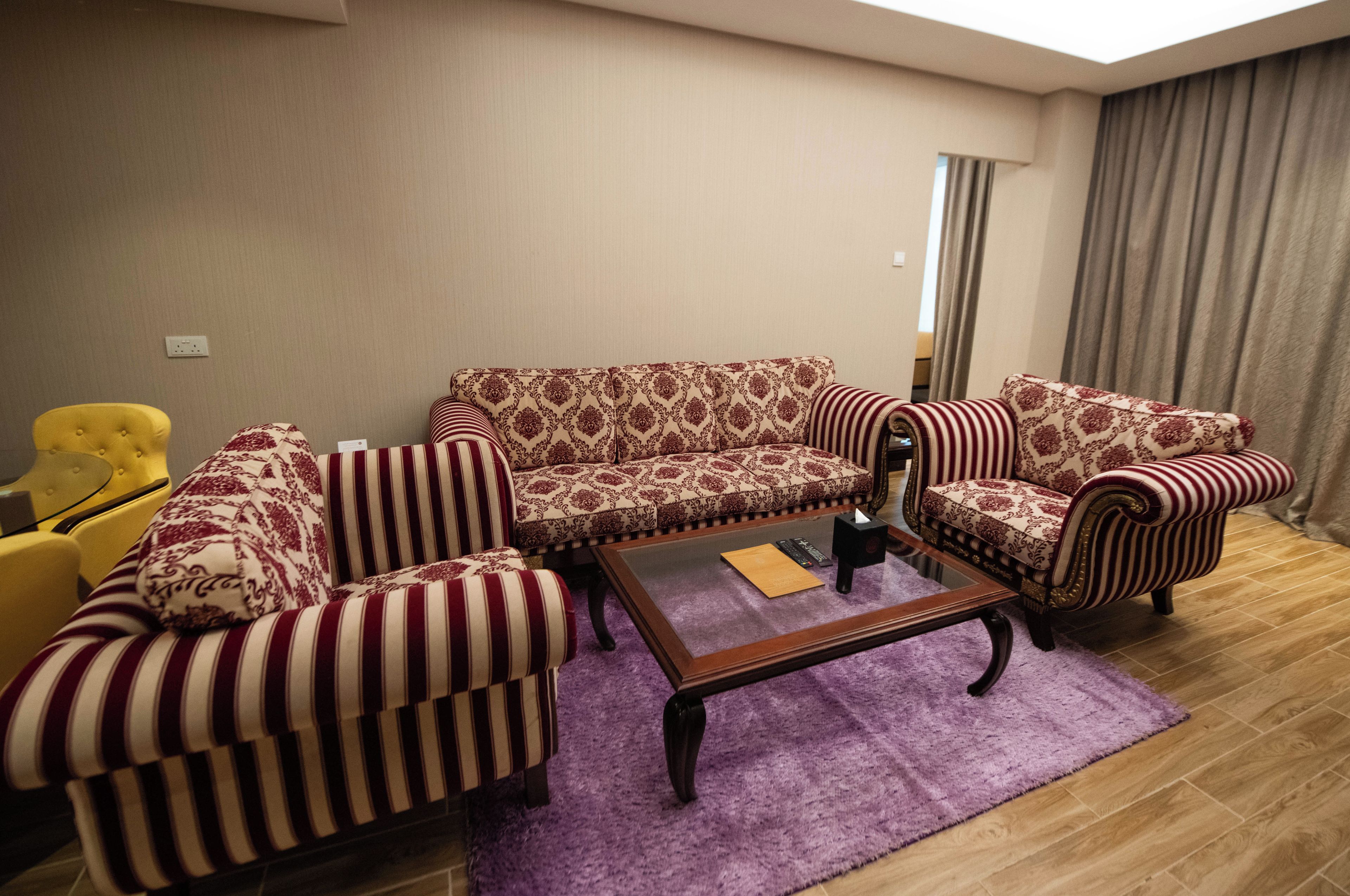 A living room with a patterned sofa, striped armchairs, a coffee table, and a yellow armchair.