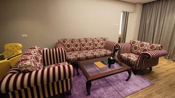 A living room with a patterned sofa, striped armchairs, a coffee table, and a yellow armchair.